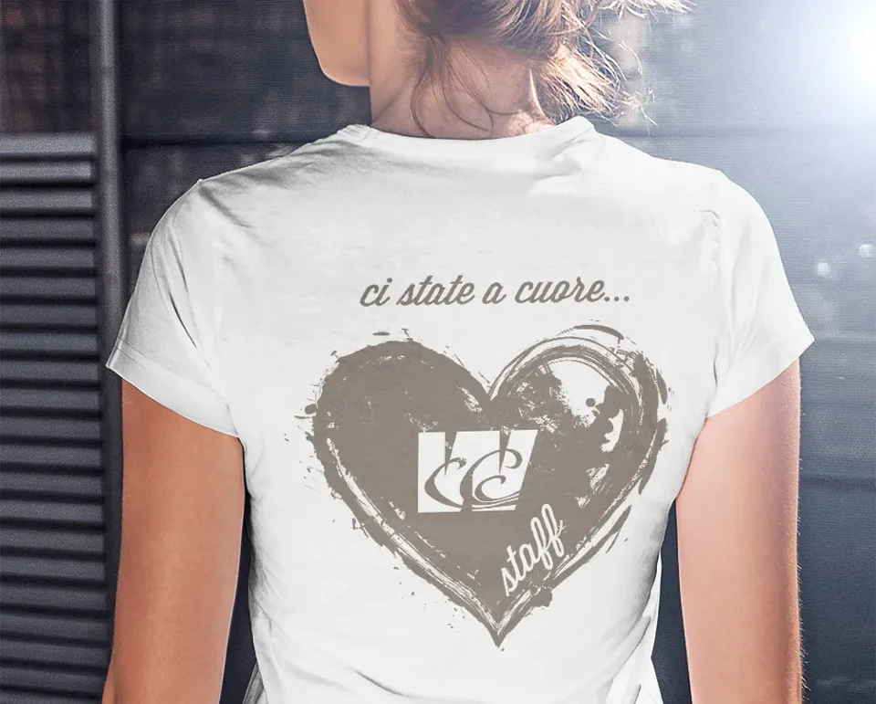 Retro di una maglietta bianca dello staff con la scritta «ci state a cuore…» e un cuore grigio a pennello con il simbolo Wave
