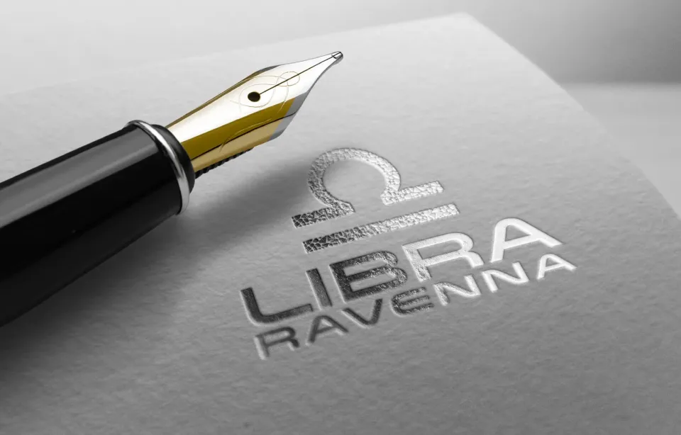 Il marchio Libra Ravenna in rilievo argento, accanto a una stilografica