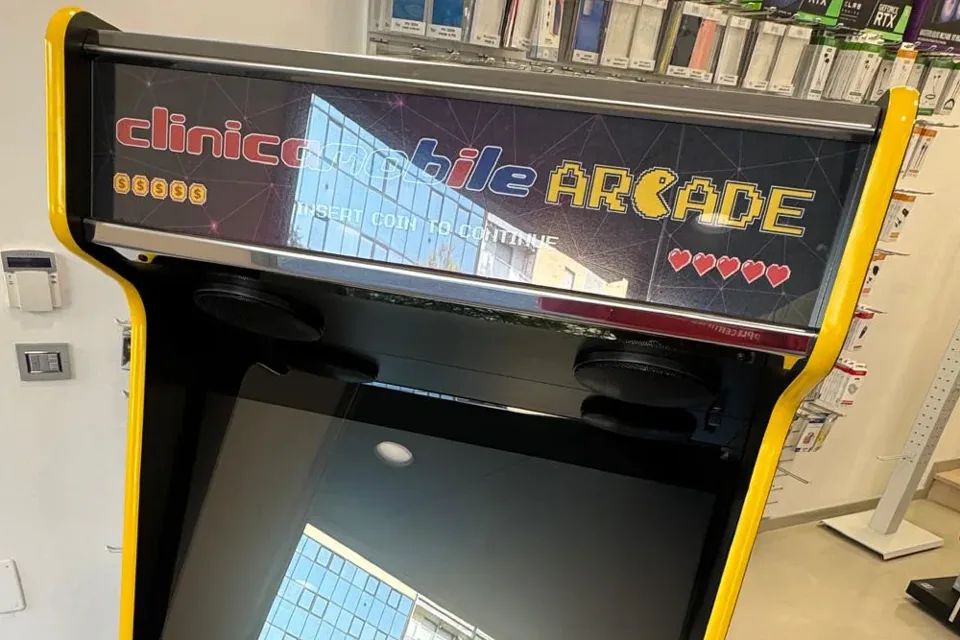 Il marquee luminoso: clinicamobile Arcade su un cielo viola attraversato da linee, con monete e cuori