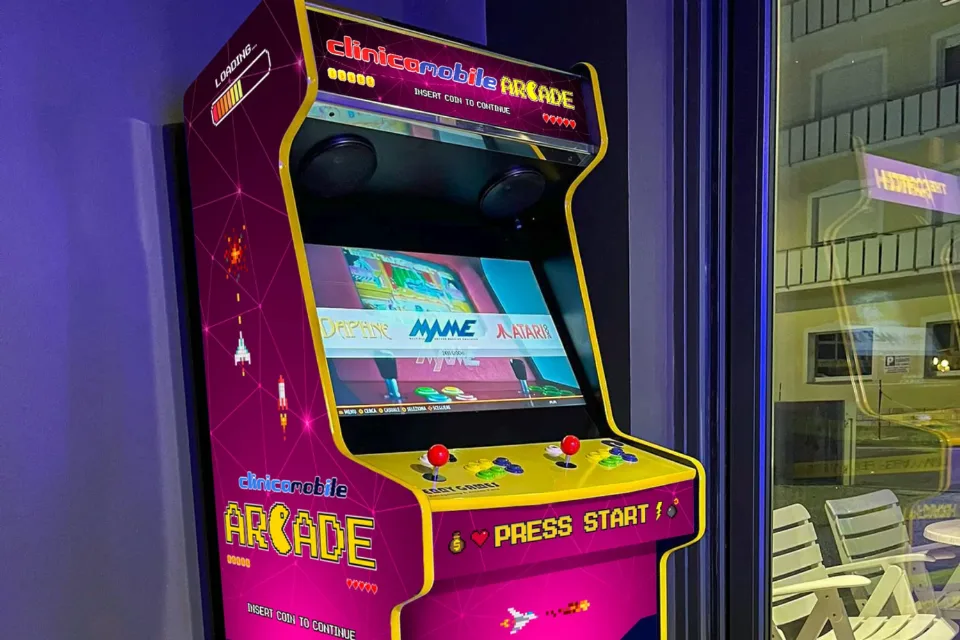 Il cabinet arcade Clinica Mobile con i fianchi in pixel art viola e fucsia